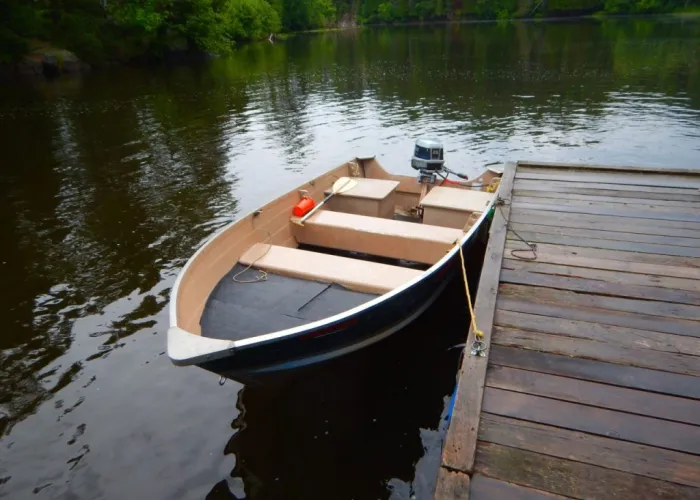 A boat with an outboard motor sitting on water docked