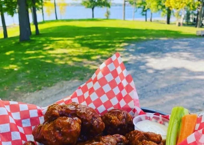 A plate full of chicken wings with a lake in the background