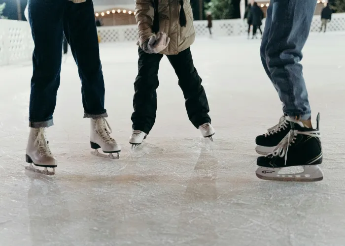 Three People Skating Outside on an Outdoor Rink.