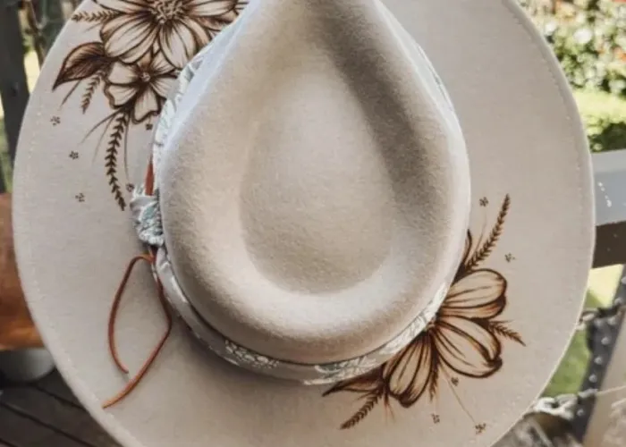 Cream coloured cowboy hat with flower designed burned onto the brim