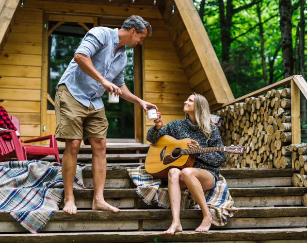 Couple enjoying coffee on the deck of a cabin in the woods outside Bancroft, Ontario